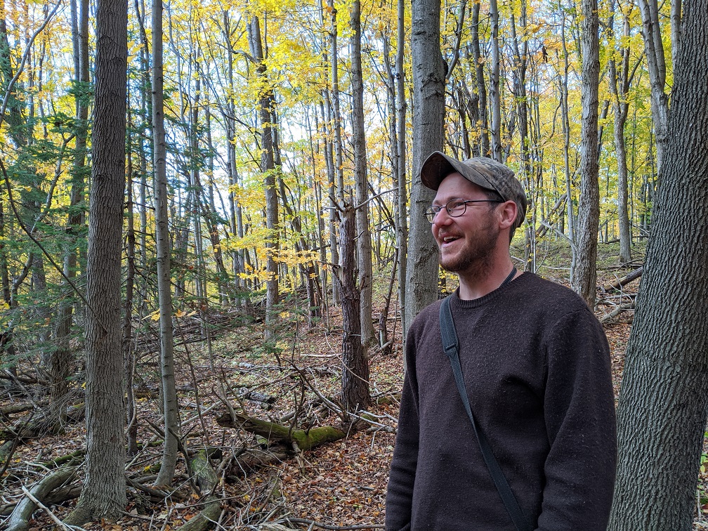 a colour photo of a man laughing in a forest. 
