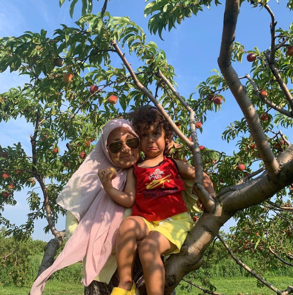a colour photo of a woman and child sitting in a fruiting tree.