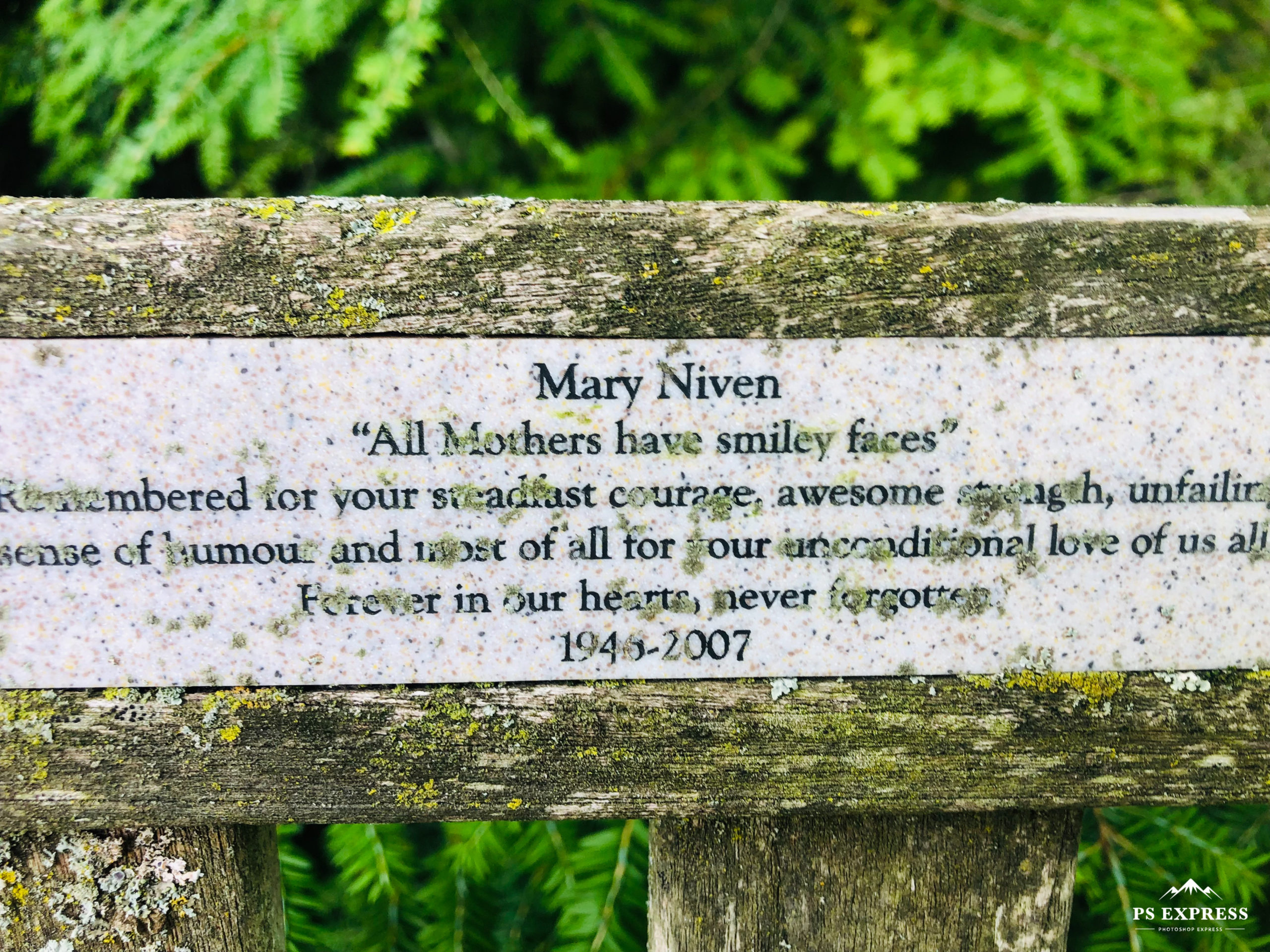 colour photo of a bench plaque with moss growing on it that reads: 
Mary Niven
"All Mother's have smiley faces."
Remembered for their steadfast courage, awesome strength, unfailing humour, and most of all our unconditional love of us all. Forever in our hearts, never forgotten. 1946-2007