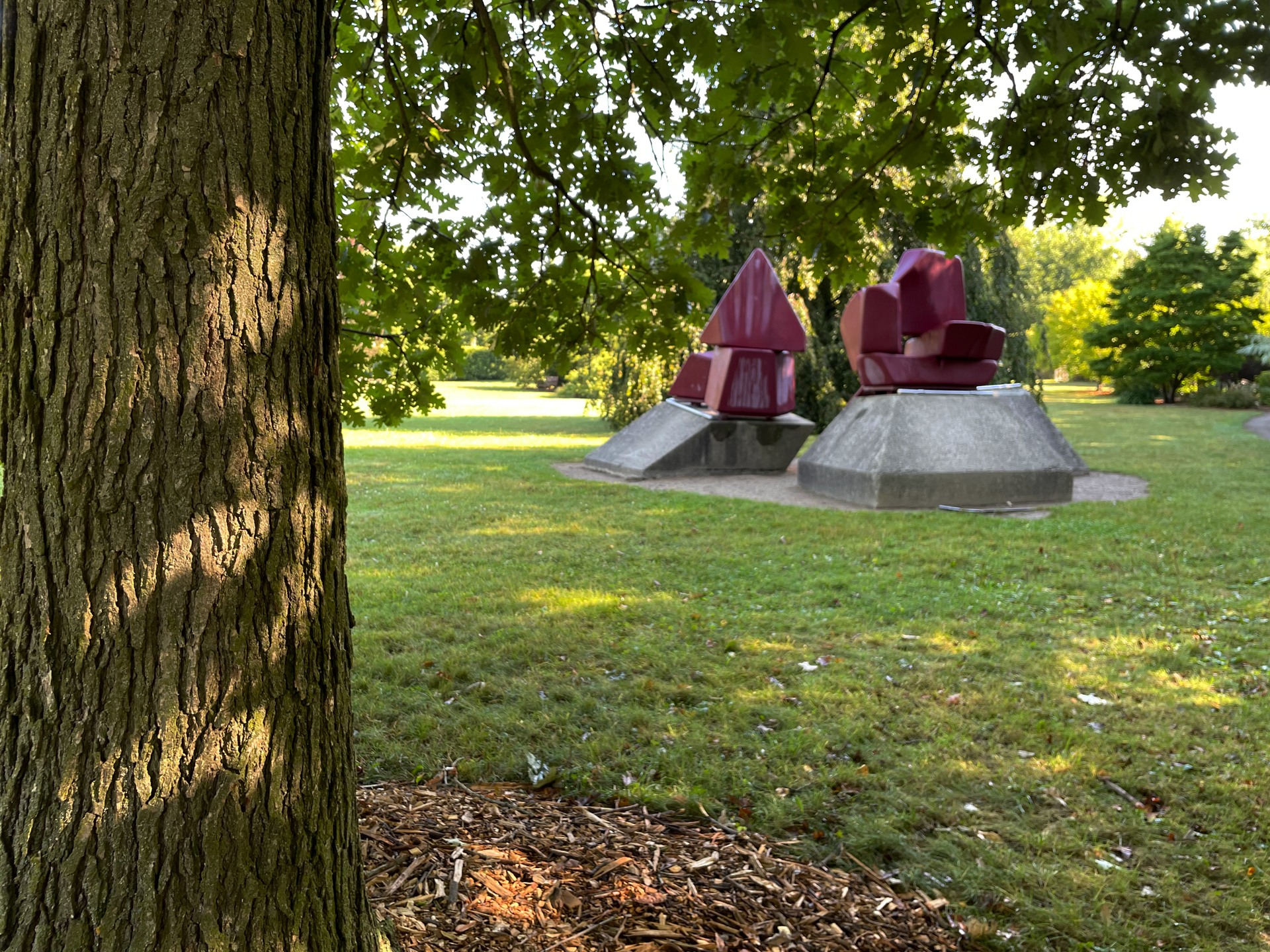 a colour photo of a sculpture in a park from under a tree on a rainy day
